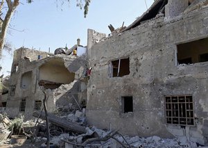 This photo released by the Syrian official news agency SANA, shows damaged buildings at the scene of an explosion along the road to the airport in southeast Damascus, Syria, Sunday, July 2, 2017.