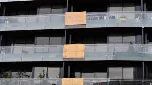 Balconies in this Melbourne apartment building have been patched up with wood following multiple glass explosions.