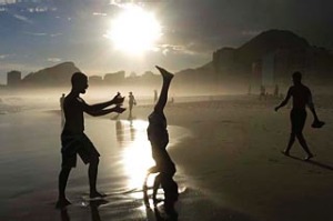 A boy does a headstand at sunset on Copacabana Beach.