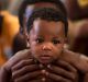 A man from Nigeria holds his 6 months old baby, on their way to Italy after being rescued along with more than 600 ...