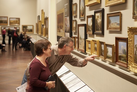 Photograph of visitors in a gallery looking at paintings