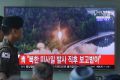 South Korean soldiers walk past a TV news report showing a file image of a missile being test-launched by North Korea.