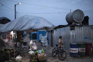 A Syrian boy stands with his bike near a shop in the Kawergosk refugee camp in northern Iraq, Saturday, April 8, 2017.