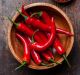 Red Hot Chili Peppers in wooden bowl on dark wooden background