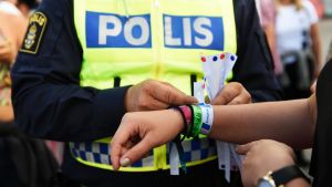 A police officer attaching a bracelet with the text "tafsainte", meaning don't grope, to a visitor's wrist at the ...