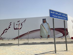 FILE- In this Monday, July 3, 2017 file photo, an image of Qatar's emir, Sheikh Tamim bin Hamad Al Thani, graces a billboard featuring the slogan "We are all Tamim" in Doha, Qatar.