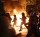 Police officers are silhouetted by fires lit by demonstrators during the protests this week.