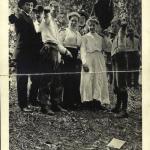 Four men, two women, one boy, fists raised, holding black flag. Labor Day leafle