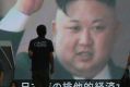 People walk in front of a TV image of North Korean leader Kim Jong-un shown on a large screen after a missile landed in ...