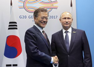 South Korean President Moon Jae-in, left, shakes hands with Russian President Vladimir Putin on the first day of the G-20 summit in Hamburg Germany, Friday July 7, 2017.