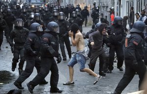 A man runs between riot Police officers during a protest against the G-20 summit in Hamburg, northern Germany, Friday, July 7, 2017. The leaders of the group of 20 meet July 7 and 8.