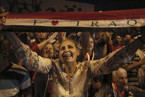 Iraqis celebrate in Tahrir square while holding national flags as they wait for the final announcement of the defeat of the Islamic state militants, in Baghdad, Iraq, Sunday, July 9, 2017.