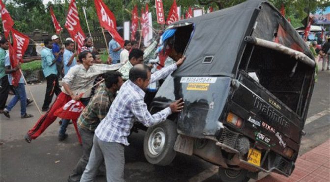 Striking Indian workers pushing over a scab van