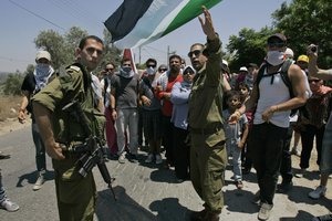 Israeli soldiers stand with Palestinians and foreign activists who damaged a part of the Israeli security barrier near the West Bank town of Qalqiliya, Monday, July 11, 2011