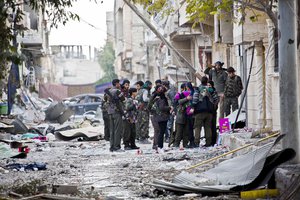 In this Wednesday, Nov. 19, 2014, file photo, fighters from Kurdish popular defense units YPJ (women) and YPG (men) gather during a short break before heading out to fight for new positions in Kobani, Syria.