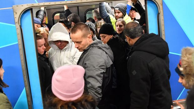 Passengers try to squeeze aboard a packed train.