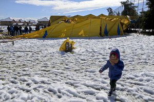 A boy walks next to a Los Pollitos circus destroy after a snowfall in Santiago, Chile, Saturday, July 15, 2017.