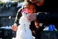 Girls make a snowman at San Cristobal hill in Santiago, Chile.