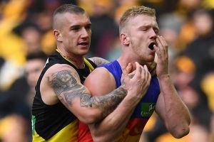 Brisbane's Nick Robertson clutches his face after an incident involving Richmond's Dustin Martin.