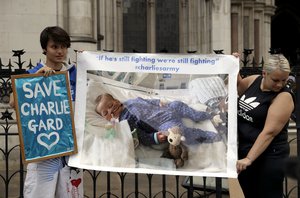 Supporters of critically ill baby Charlie Gard hold up a photograph of him after his court case finished for the day at the High Court in London, Friday, July 14, 2017.