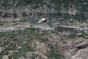 A helicopter flies above the rugged terrain along the banks of the East Verde River during a search and rescue operation for victims of a flash flood on Sunday, July 16, 2017, in Payson, AZ.  At least eight people were killed and one is still missing after floodwaters swept them away at the Cold Springs swimming hole just North of Payson on Saturday, July 15, 2017. (AP Photo/Ralph Freso)