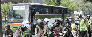 Motorcyclists, police and pedestrians share roads and footpaths in Jakarta, Indonesia