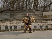 An elderly Kashmiri vendor sells Kangris or fire pots, on a cold morning in Srinagar, India, Monday, Nov. 24, 2014. Kangri is an age old device for keeping warm, consisting of a decoratively woven yellow wicker case housing an earthen pot for burning charcoal. (AP Photo/Mukhtar Khan)