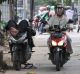 A motorbike rests on his bike as another passes him on a footpath in Jakarta on Tuesday. 