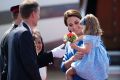 Britain's Kate, the Duchess of Cambridge holds her daughter Princess Charlotte as they arrive at the airport in Berlin, ...