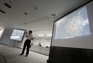 Tokyo Electric Power Company (Tepco) spokesman Takahiro Kimoto speaks during the press conference while showing video image shot by an underwater robot into Fukushima plant to search for melted fuel at the TEPCO headquarters in Tokyo Wednesday, July 19, 2017. (AP Photo/Eugene Hoshiko)