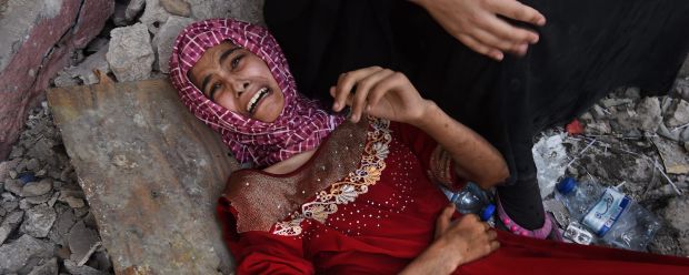 Fifteen year old Tabarek who is wounded and can no longer walk lies at the feet of her family as they rest for a few ...