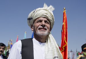 In this Wednesday, Aug. 19, 2015 photo, Afghanistan President Ashraf Ghani listens to the national anthem after putting flowers on the "Independence Minaret" monument during an Independence Day ceremony in Kabul, Afghanistan.