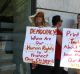 Women hold up signs criticising vaccination in Australia.