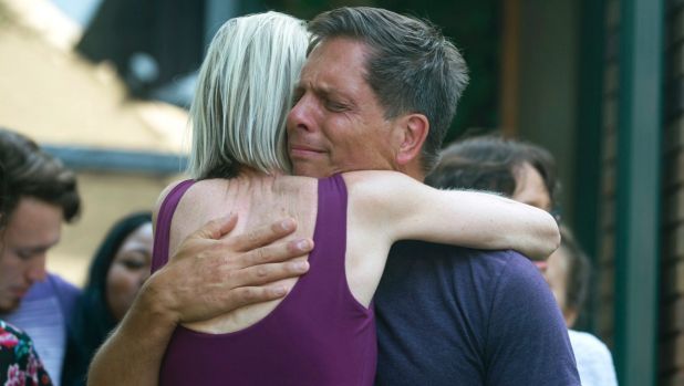 Don Damond, Justine's fiance, is comforted outside his home as demonstrators march by during the Peace and Justice March ...