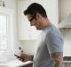 Man in pajamas texting in kitchen in morning Social media and relationships.