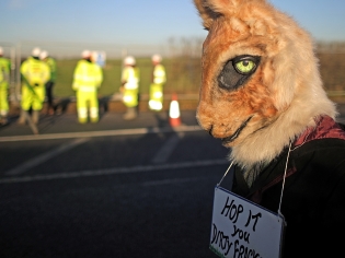 An environmental activist dressed as a rabbit, with a sign saying 'hop it you dirty frackers' as workmen begin the construction of the shale gas fracking site on January 5, 2017