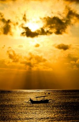 Beautiful orange sky Bali Sunset with traditional fishing boat in the foreground.