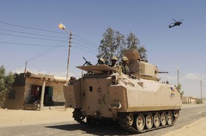 In this Tuesday, May 21, 2013, file photo, Egyptian Army soldiers patrol in an armored vehicle backed by a helicopter gunship during a sweep through villages in Sheikh Zuweyid, northern Sinai, Egypt.