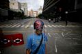 A demonstrator wearing a mask adorned with rosaries stands near a barricade during a 48-hour general strike beginning ...