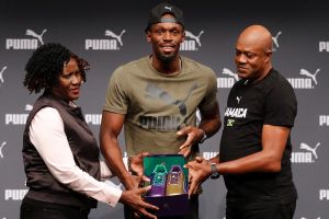 Usain Bolt with his parents, Jennifer and Wellesley, and the purple and gold shoes he will run in at the world titles.