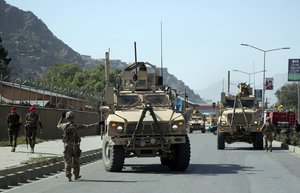 A U.S. soldier directs his colleague at the site of a bomb attack that targeted several armored vehicles belonging to forces attached to the NATO Resolute Support Mission, in downtown of Kabul, Afghanistan