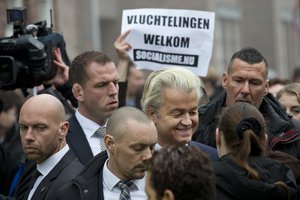 A protestors holds a sign reading "Refugees Welcome" as firebrand anti-islam lawmaker Geert Wilders, center, greets well-wishers during an election campaign stop in Spijkenisse, near Rotterdam, Netherlands, Saturday Feb. 18, 2017.