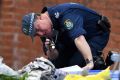 A police officer searches items from a property in Lakemba as part of an investigation into an alleged terrorism plot.