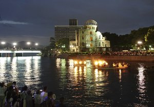 In this Saturday, Aug. 5, 2017, photo, organizers of a peace prayer event light up torches on floats on the Motoyasu River next to the Atomic Bomb Dome in Hiroshima, western Japan, on the eve of the 72nd anniversary of the first U.S. atomic attack that killed 140,000 people in the city.