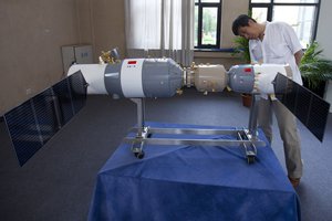 A visitor checks a model showing Shenzhou 8 spacecraft, right, docked with Tiangong-1 space lab module, left, at an exhibition in Beijing, China, Wednesday, June 13, 2012.