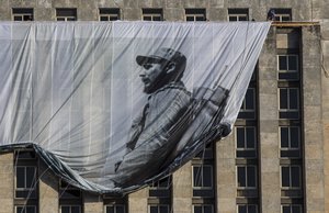 Men hang a giant banner with a picture of Cuba's late leader Fidel Castro as a young revolutionary, from the Cuban National Library building in Havana, Cuba, Sunday, Nov. 27, 2016.