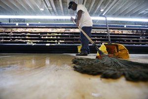 Randy Davis, manager at the Circle Food Store, mops the floor after the store flooded from the pasts weekend's rainstorms, in New Orleans, Monday, Aug. 7, 2017. (AP Photo/Gerald Herbert)