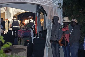 Migrants line up at the end of Roxham Road in Champlain, N.Y., while heading to an unofficial border station across from Saint-Bernard-de-Lacolle, Quebec, early Tuesday morning, Aug. 8, 2017