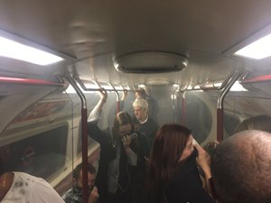 In this photo provided by Joe Bunting, commuters cover their mouths as smoke fills the carriage of a Bakerloo line train, near Oxford Circus in London, Friday, Aug. 11, 2017.