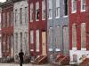 Pedestrians pass by a row of boarded up houses in east Baltimore on August 8, 2017. Baltimore, a city of 2.8 million, is troubled by drug use, poverty and racial segregation problems. In 2016 violent crime in Baltimore was up 22 percent and murders up 78 percent, according to Attorney General Jeff Sessions. / AFP PHOTO / MANDEL NGAN